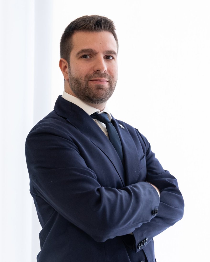 Portrait of Jacopo Manotti in a navy jacket, arms crossed, in a bright office